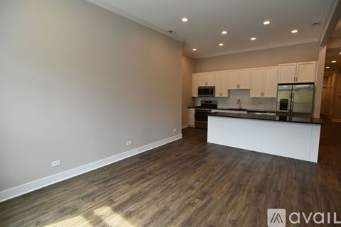 A spacious kitchen with wooden flooring and white cabinets.