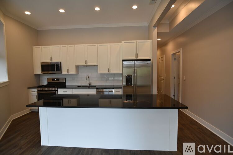 A kitchen with white cabinets and a black countertop.