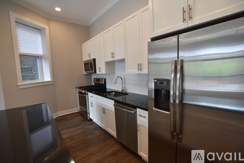 A kitchen with white cabinets and a black countertop.