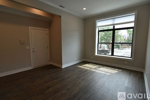 A room with wooden floors and a window showing a street view.