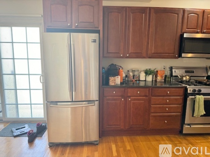 A kitchen with a stainless steel refrigerator and wooden cabinets.
