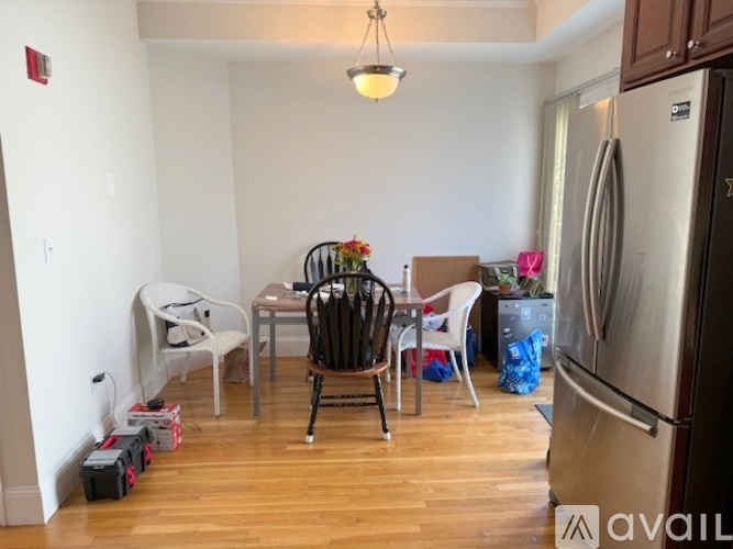 A kitchen with a refrigerator, a dining table with chairs, and a few items scattered on the floor.