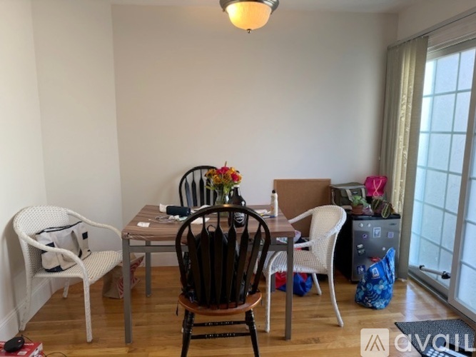A dining room with a table, chairs, and a vase of flowers.