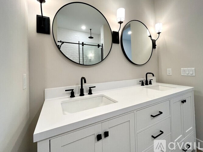 A white bathroom vanity with a round mirror and two wall lights.
