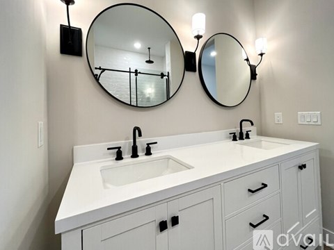 A white bathroom vanity with a round mirror and two wall lights.