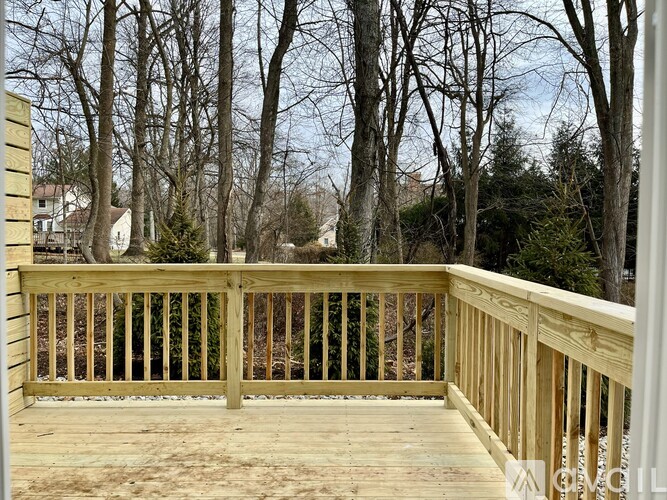A wooden deck with a railing and trees in the background.