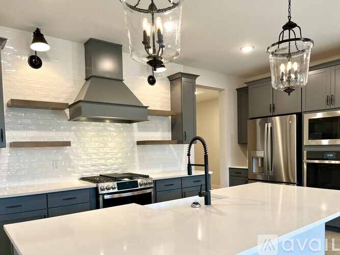 A modern kitchen with a white countertop and stainless steel appliances.