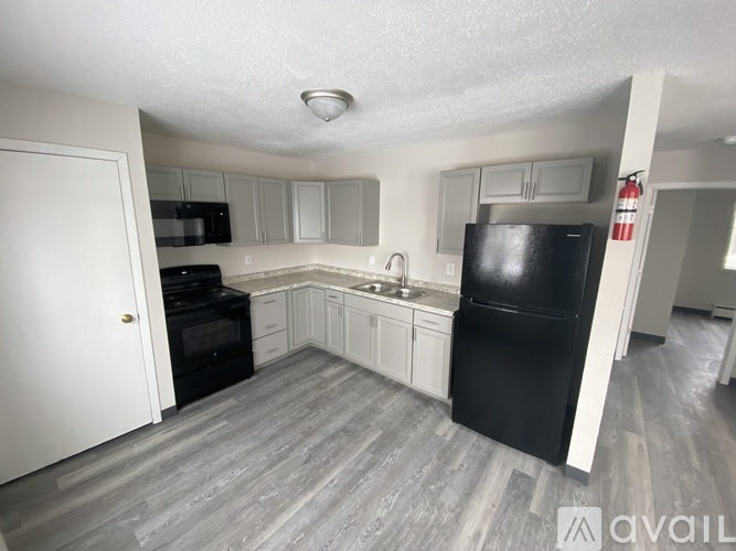 A black refrigerator sits in a kitchen with white cabinets and a white door.