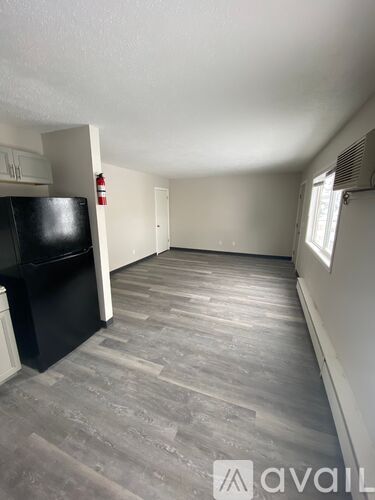 A kitchen area with a black fridge and a grey floor.