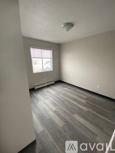 A room with a window and wooden flooring.