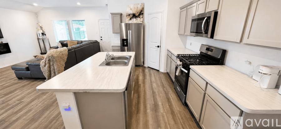 A modern kitchen with a wooden floor and white cabinets.
