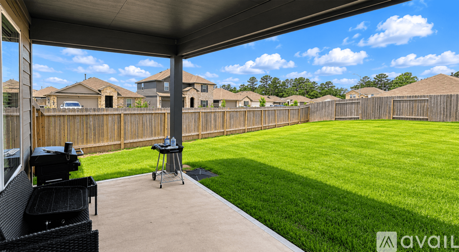 A patio with a grill and chairs overlooks a grassy backyard.