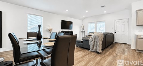 A modern living room with a black leather sofa and a glass dining table.