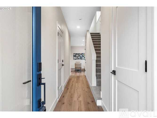 A long hallway with a blue door on the left and a staircase in the distance.