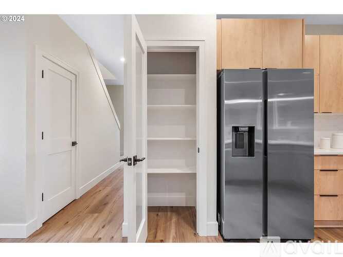 A modern kitchen with a refrigerator, wooden cabinets, and a white door.