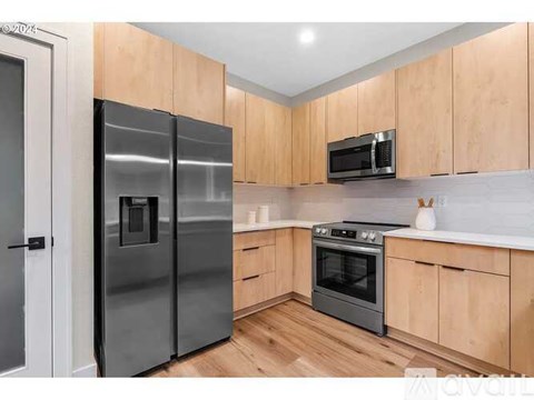 A kitchen with wooden cabinets and a black fridge.