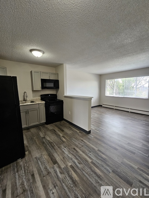 A kitchen area with a black refrigerator, microwave, and oven.
