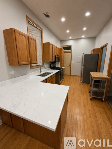 A kitchen with wooden cabinets and a white marble counter.