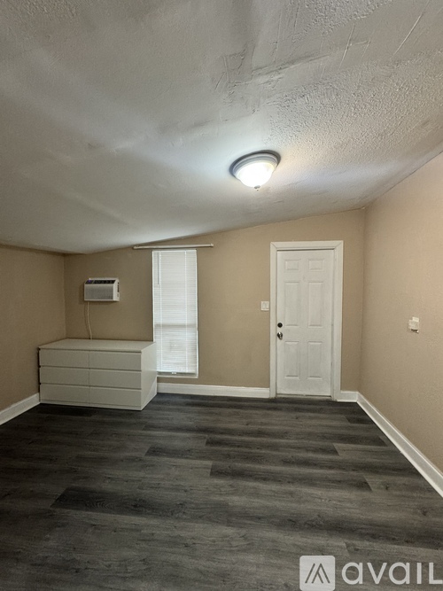 A room with a white ceiling, a window with blinds, a white door, and a white dresser.
