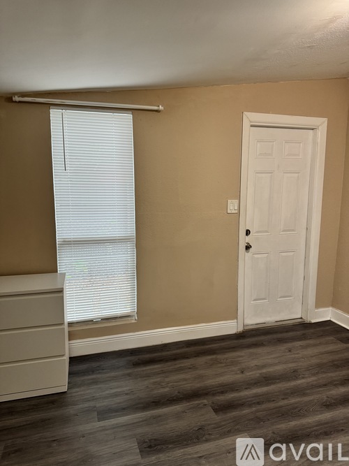 A room with a white door and a window with blinds.