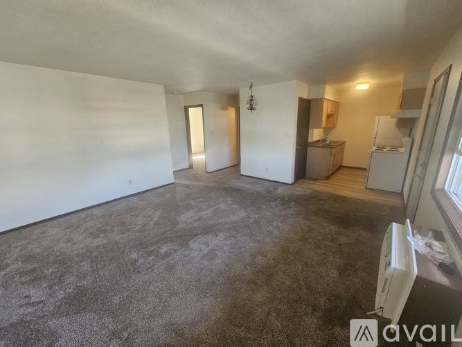 A spacious room with a grey carpet and white walls.