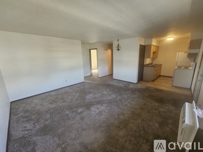 A spacious room with a grey carpet and white walls.