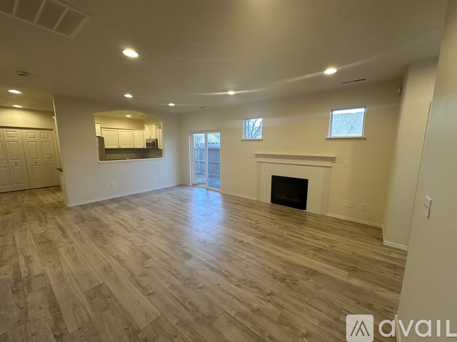 A spacious living room with wood flooring and a fireplace.
