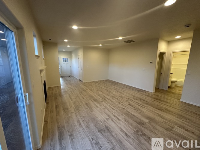 A spacious room with wooden flooring and white walls.