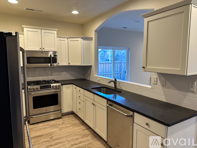 A kitchen with white cabinets and a black countertop.