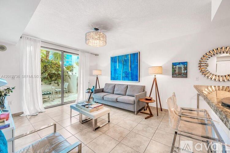 A living room with a grey couch and a painting on the wall.