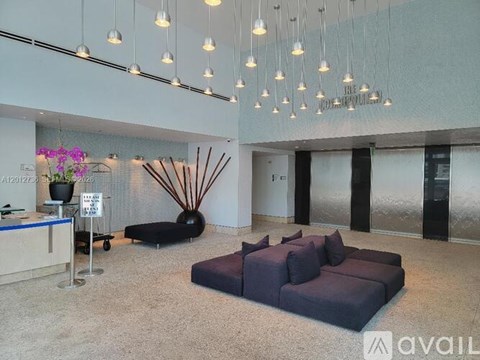 A spacious waiting area with a reception desk, sofas, and hanging lights.