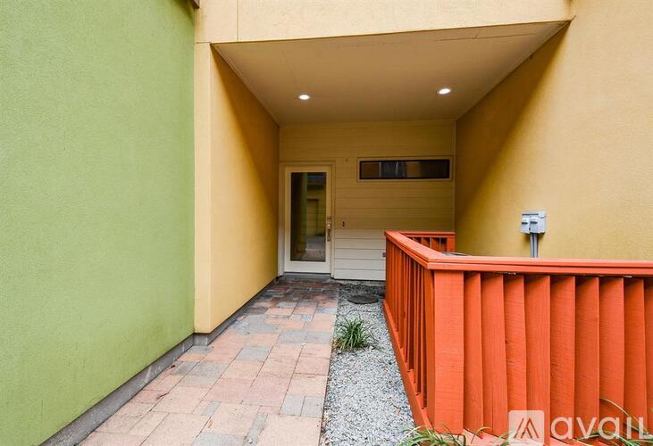 A yellow building with a white door and a small garden area.