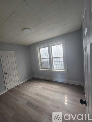 A room with a door, a window, and a wooden floor.