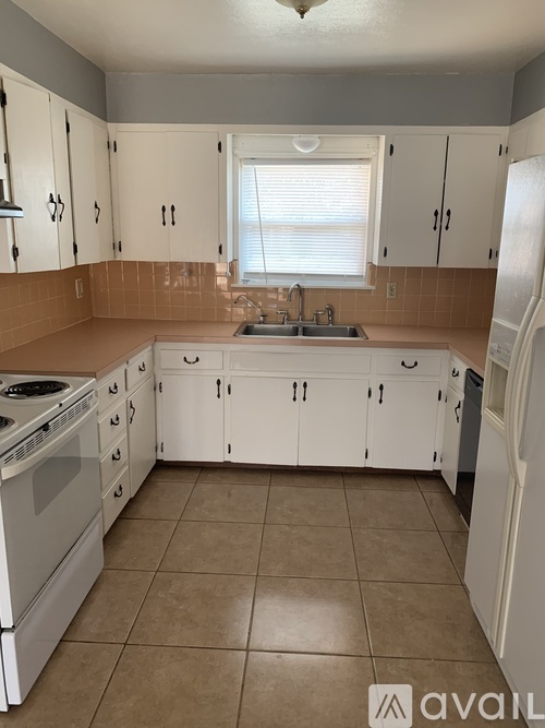 A kitchen with white cabinets and a tiled floor.