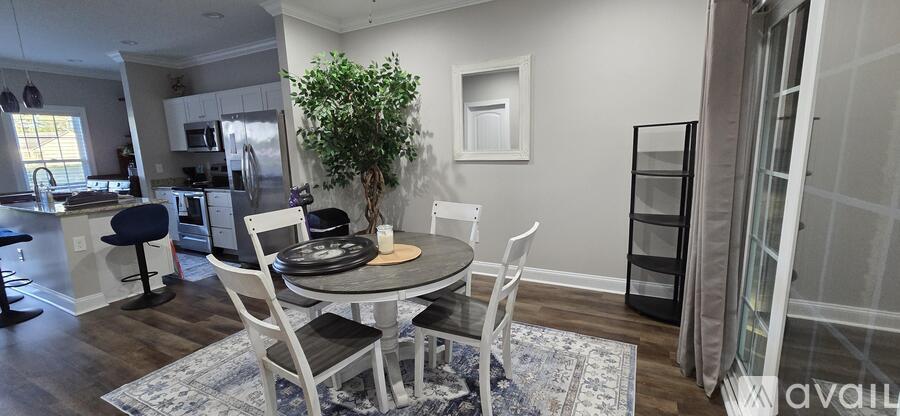 A dining room with a table set for two and a potted plant.