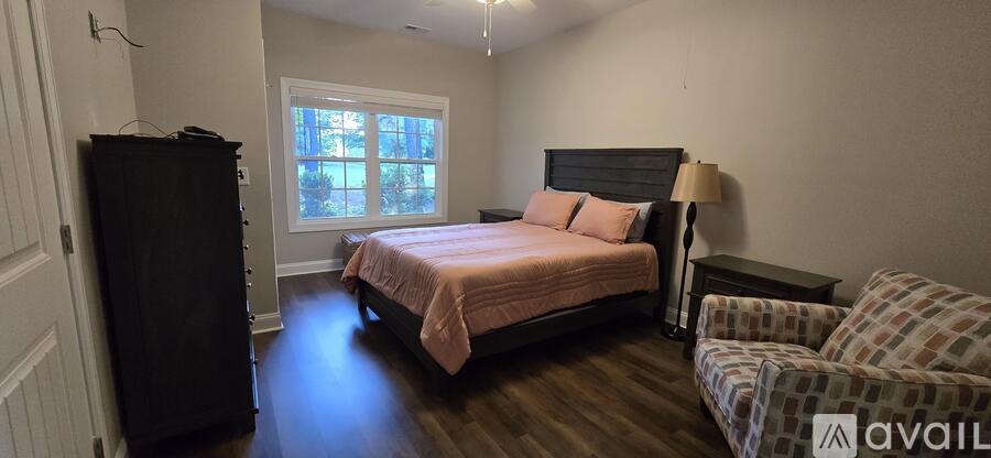 A bedroom with a bed, chair, and window.