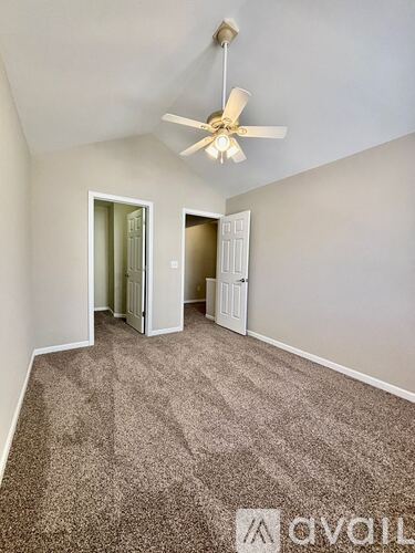 A room with a ceiling fan and carpeted floor.