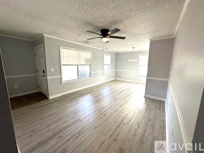 A spacious room with wood flooring and a ceiling fan.
