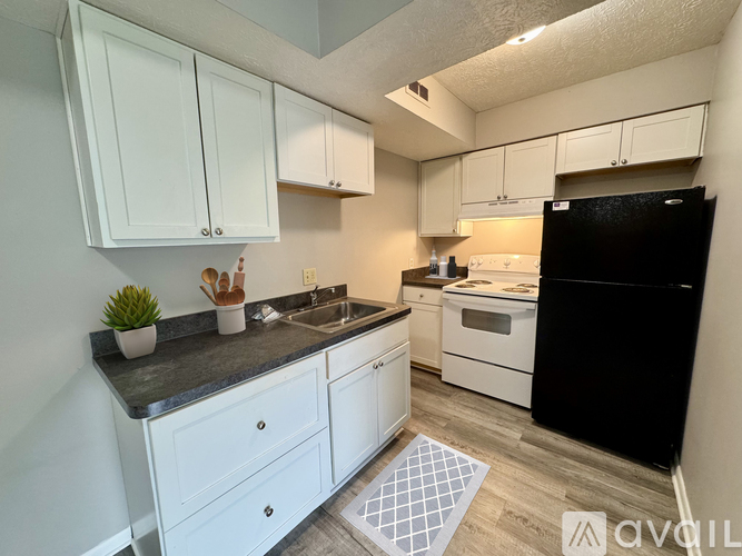 A kitchen with white cabinets and black appliances.