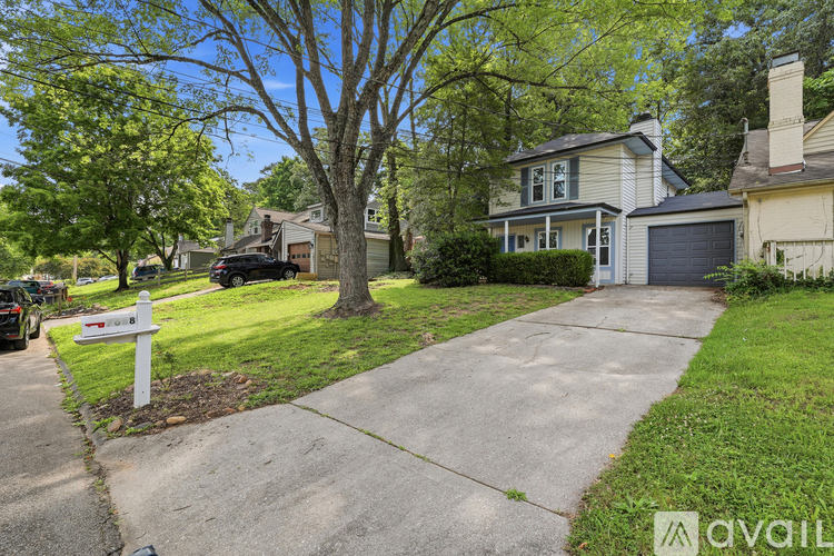A residential area with a house, driveway, and trees.