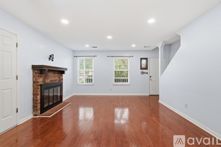 A spacious room with a fireplace and wood flooring.