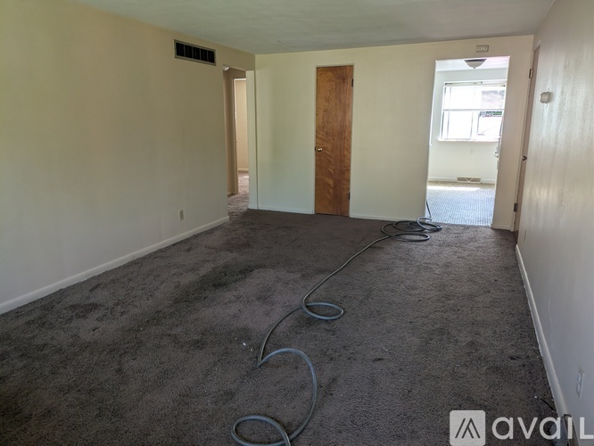 A room with a carpeted floor, a door, and a window.