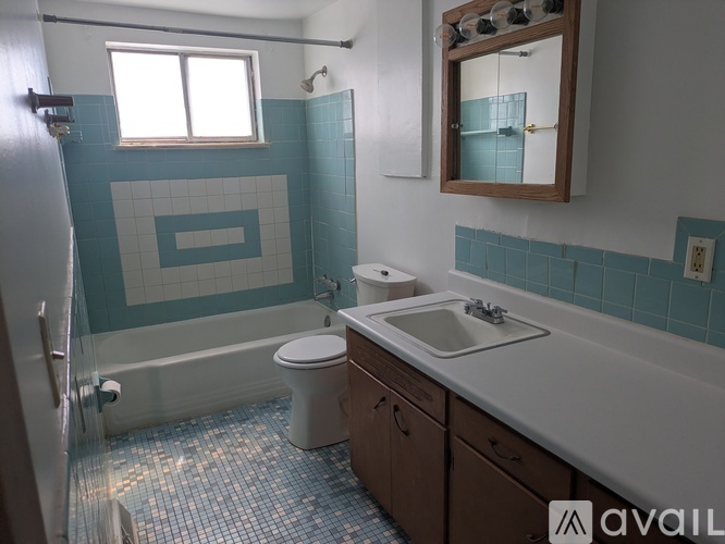 A bathroom with a white toilet, a white sink, and a blue tiled shower.