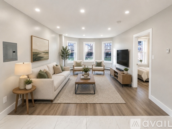 A well-lit living room with a large couch, a coffee table, and a television.