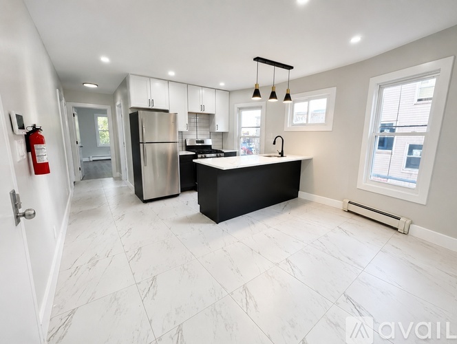 A modern kitchen with a black countertop and white marble tiles.