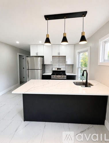 A modern kitchen with a marble countertop and black and white cabinetry.