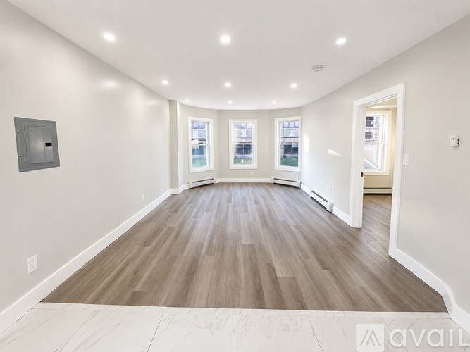 A spacious room with wood flooring and white walls.