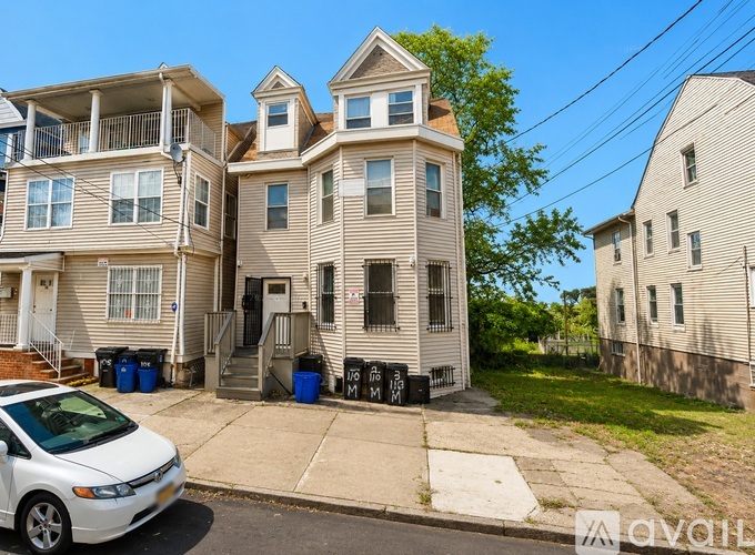 A white car is parked in front of a two-story building.