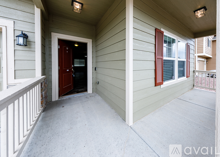 A balcony with a red door and a window with red shutters.