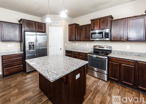 A kitchen with dark wood cabinets and a granite countertop.